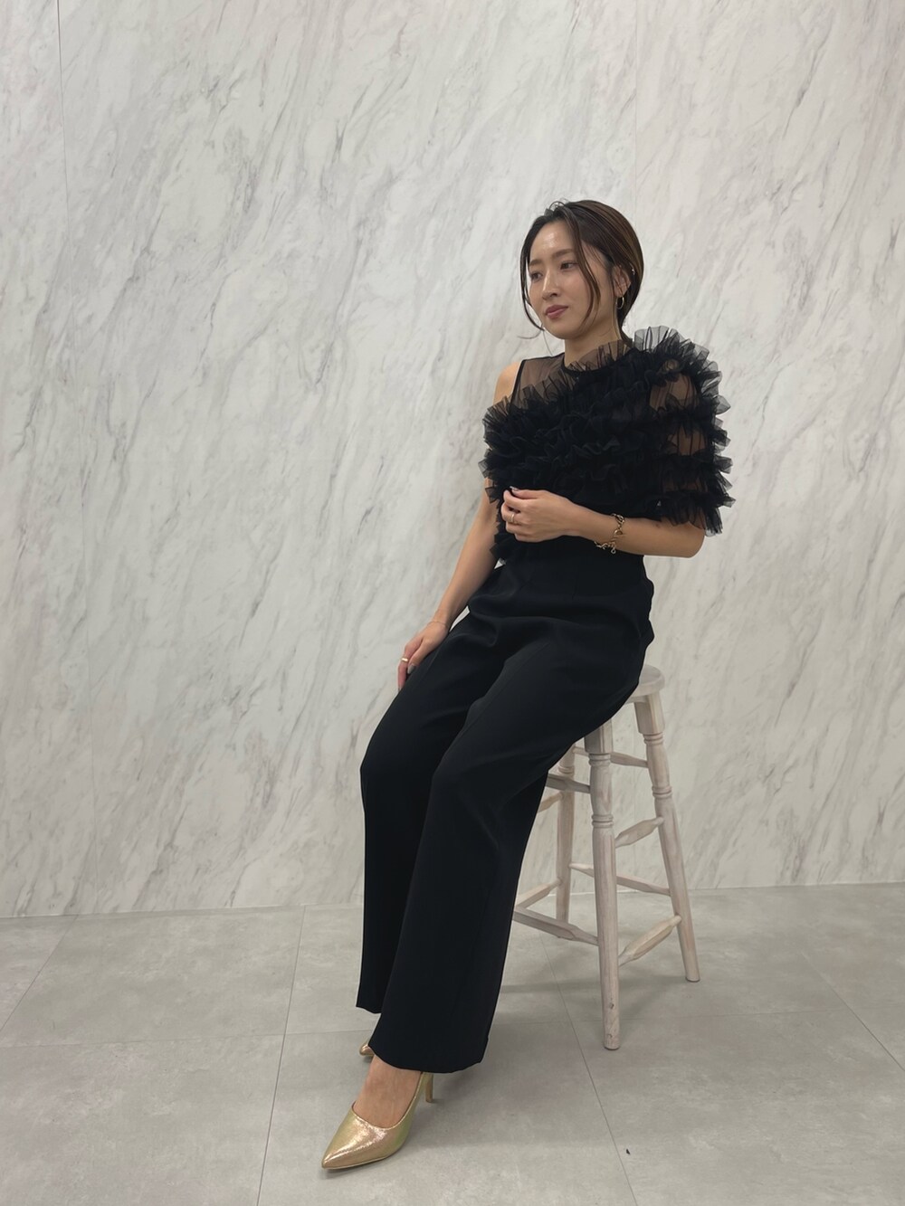 ブラック系のパンツドレス、ゴールド系のパンプスを着用したレディースの冬コーディネートの5枚目の写真