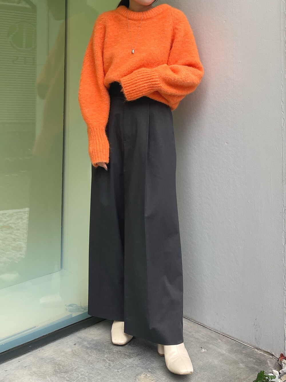 オレンジ系のニット/セーター、グレー系のその他パンツ、ホワイト系のブーツを着用したレディースの冬コーディネートの4枚目の写真