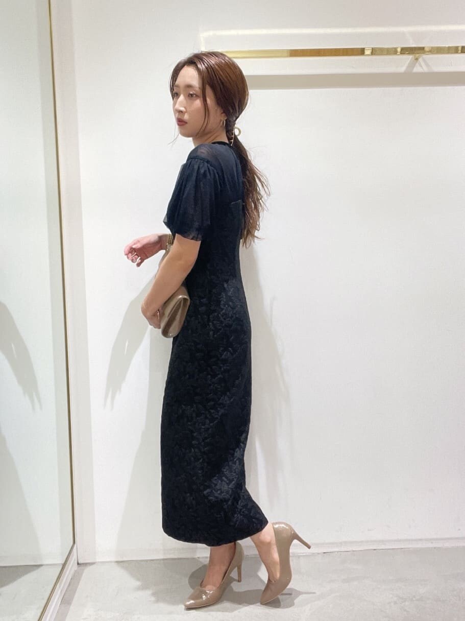 ゴールド系のクラッチバッグ、ゴールド系のパンプス、ブラック系のドレスを着用したレディースの秋コーディネートの4枚目の写真