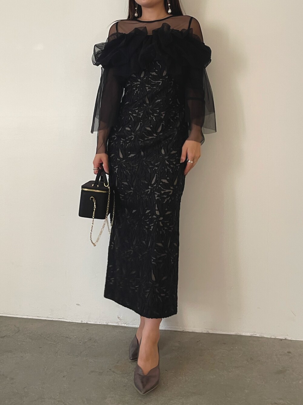 シルバー系のパンプス、ブラック系のハンドバッグ、ブラック系のドレスを着用したレディースの秋コーディネートの3枚目の写真