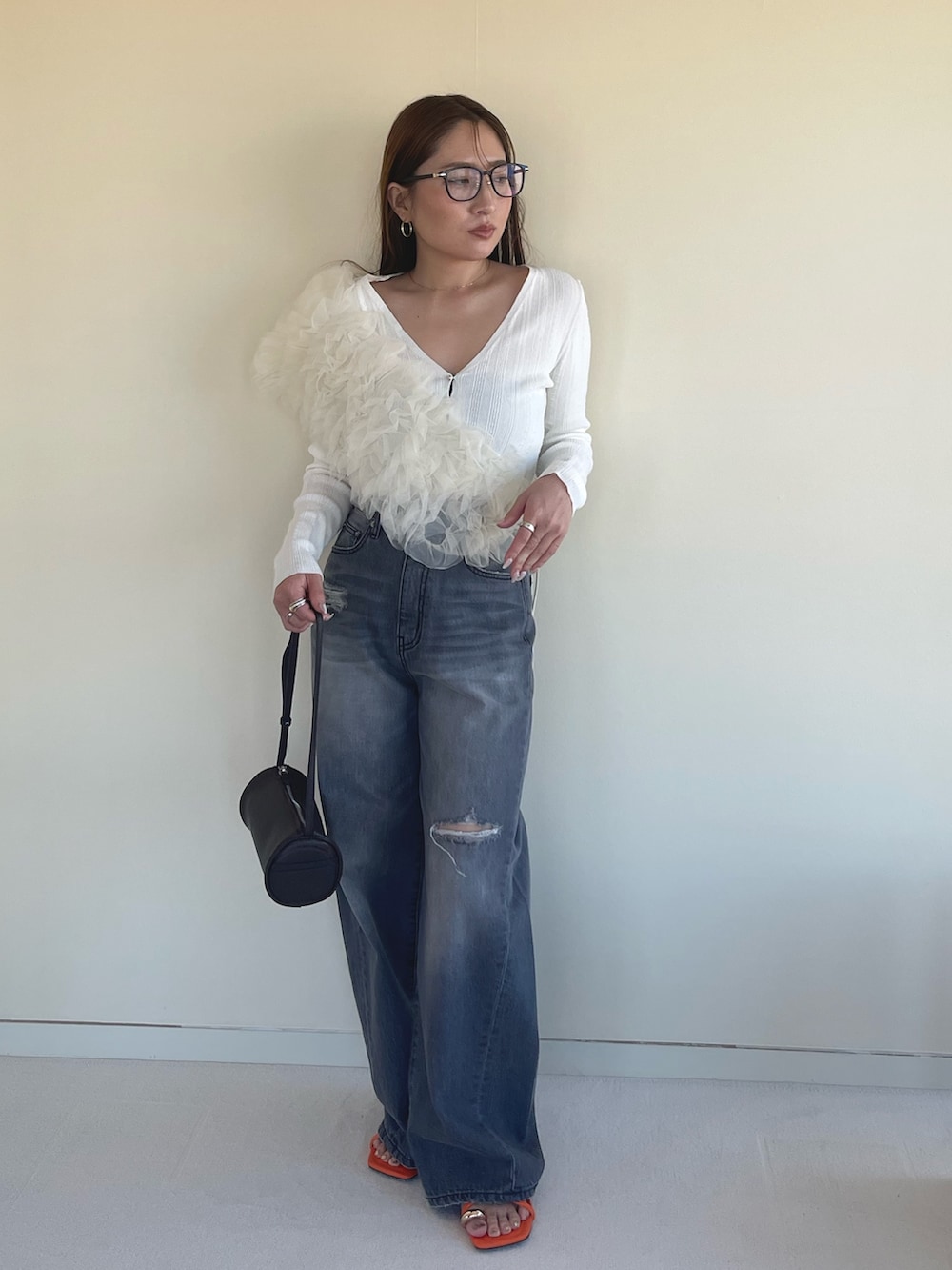 オレンジ系のサンダル、グレー系のデニムパンツ、ホワイト系のカーディガン/ボレロを着用したレディースの春コーディネートの2枚目の写真