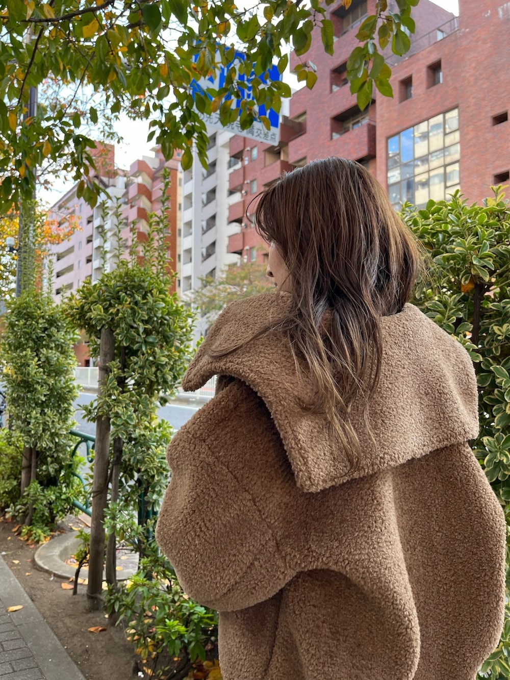 ブラウン系のブルゾン、レッド系のブーツ、ブラック系のワンピースを着用したレディースの秋コーディネートの8枚目の写真