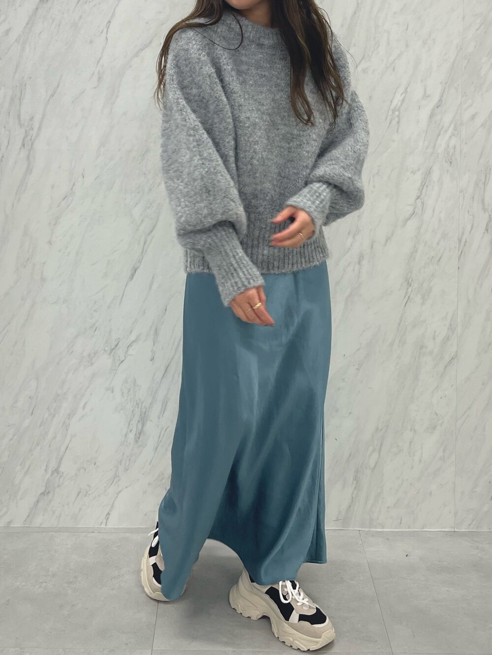 グレー系のニット/セーター、ブルー系のスカート、ブラック系のスニーカーを着用したレディースの冬コーディネートの4枚目の写真