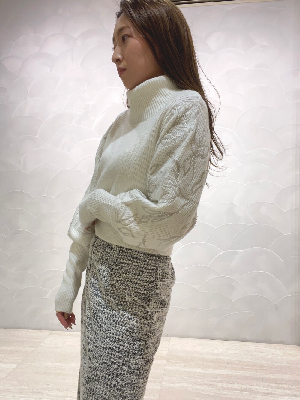 ホワイト系のニット/セーター、ブラック系のスカート、ベージュ系のブーツを着用したレディースの秋コーディネートの7枚目の写真