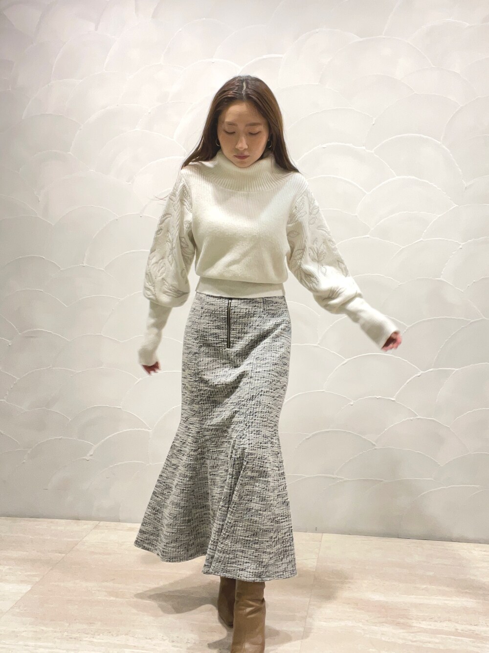 ホワイト系のニット/セーター、ブラック系のスカート、ベージュ系のブーツを着用したレディースの秋コーディネートの5枚目の写真