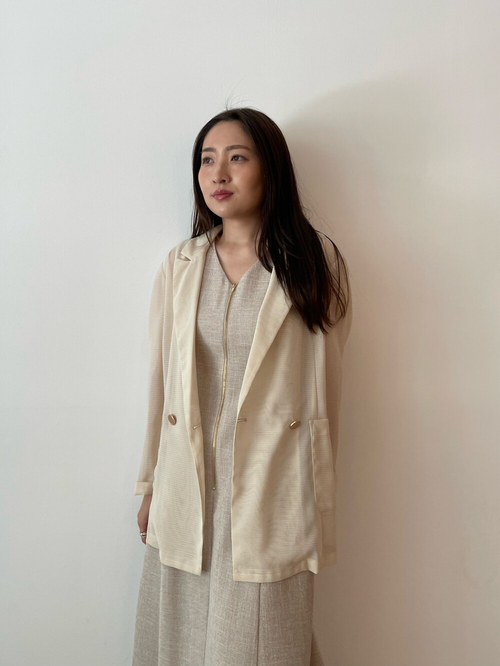 ベージュ系のワンピース、ホワイト系のサンダル、ホワイト系のテーラードジャケットを着用したレディースの夏コーディネートの4枚目の写真