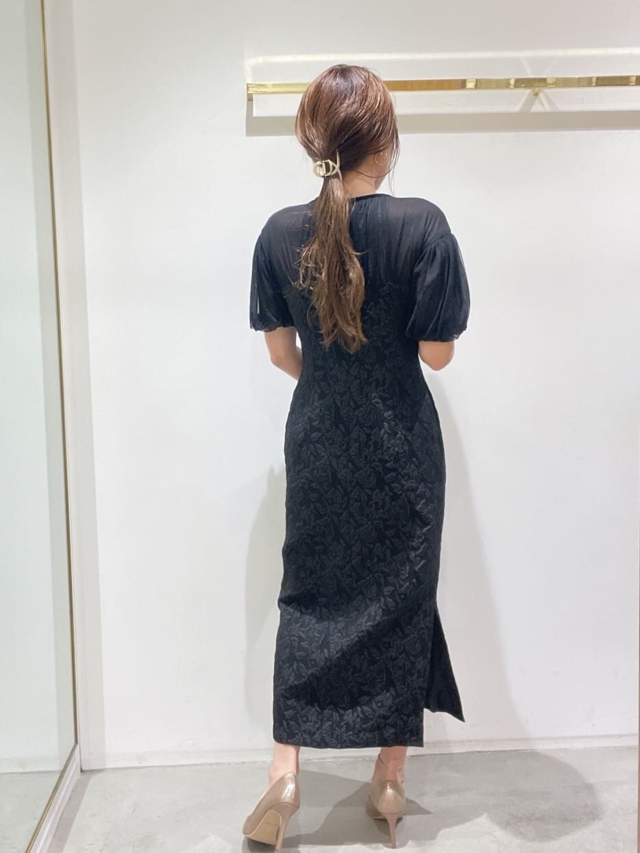 ゴールド系のクラッチバッグ、ゴールド系のパンプス、ブラック系のドレスを着用したレディースの秋コーディネートの8枚目の写真