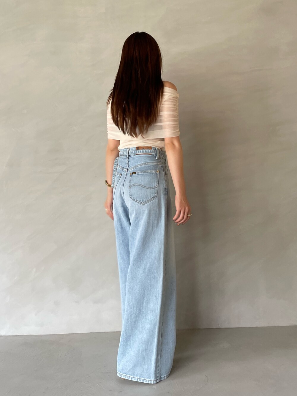 ブルー系のデニムパンツ、ホワイト系のTシャツ/カットソー、ホワイト系のサンダルを着用したレディースの夏コーディネートの6枚目の写真