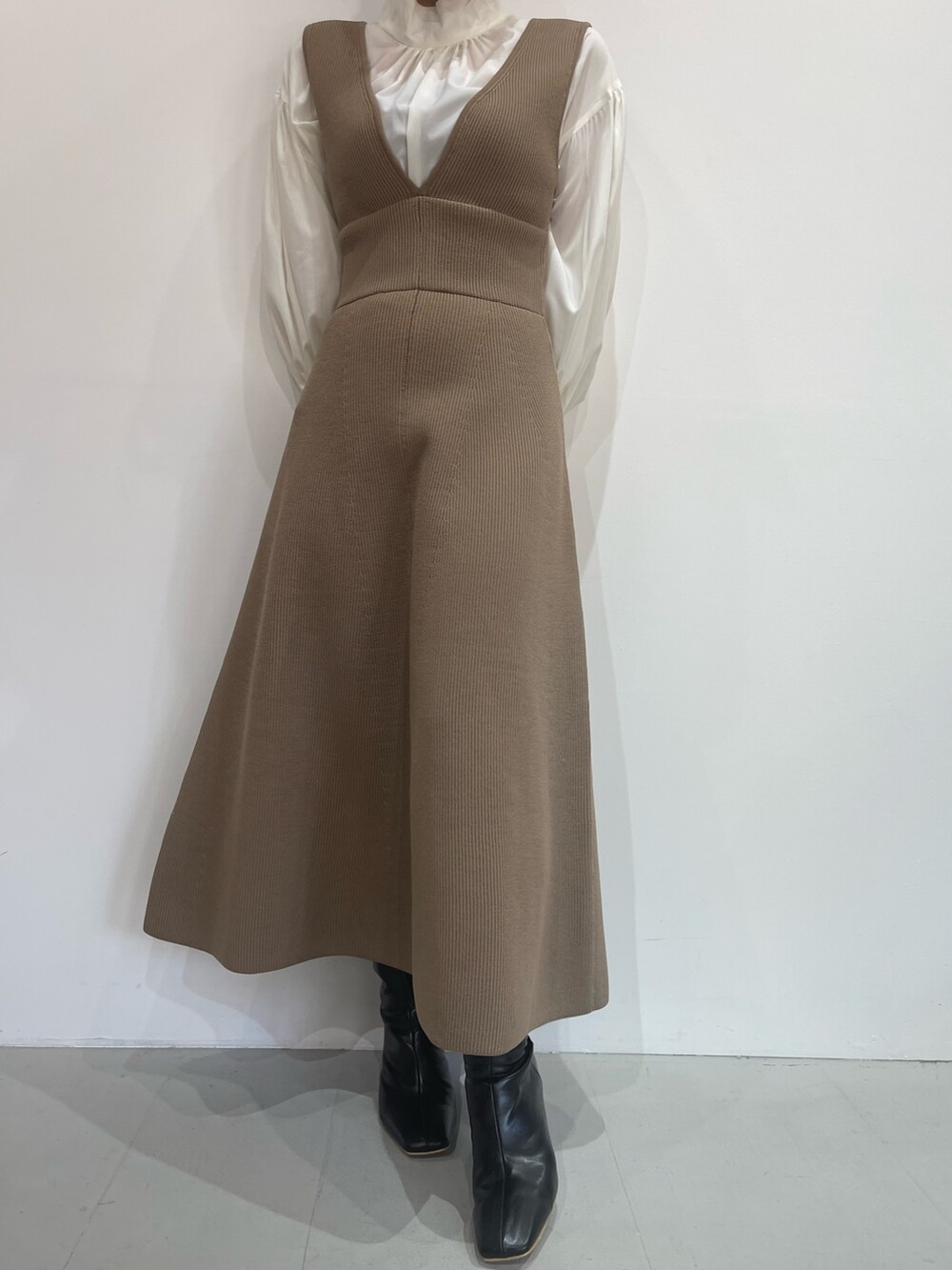 ブラック系のブーツ、ベージュ系のジャンパースカート、ホワイト系のシャツ/ブラウスを着用したレディースの秋コーディネートの7枚目の写真