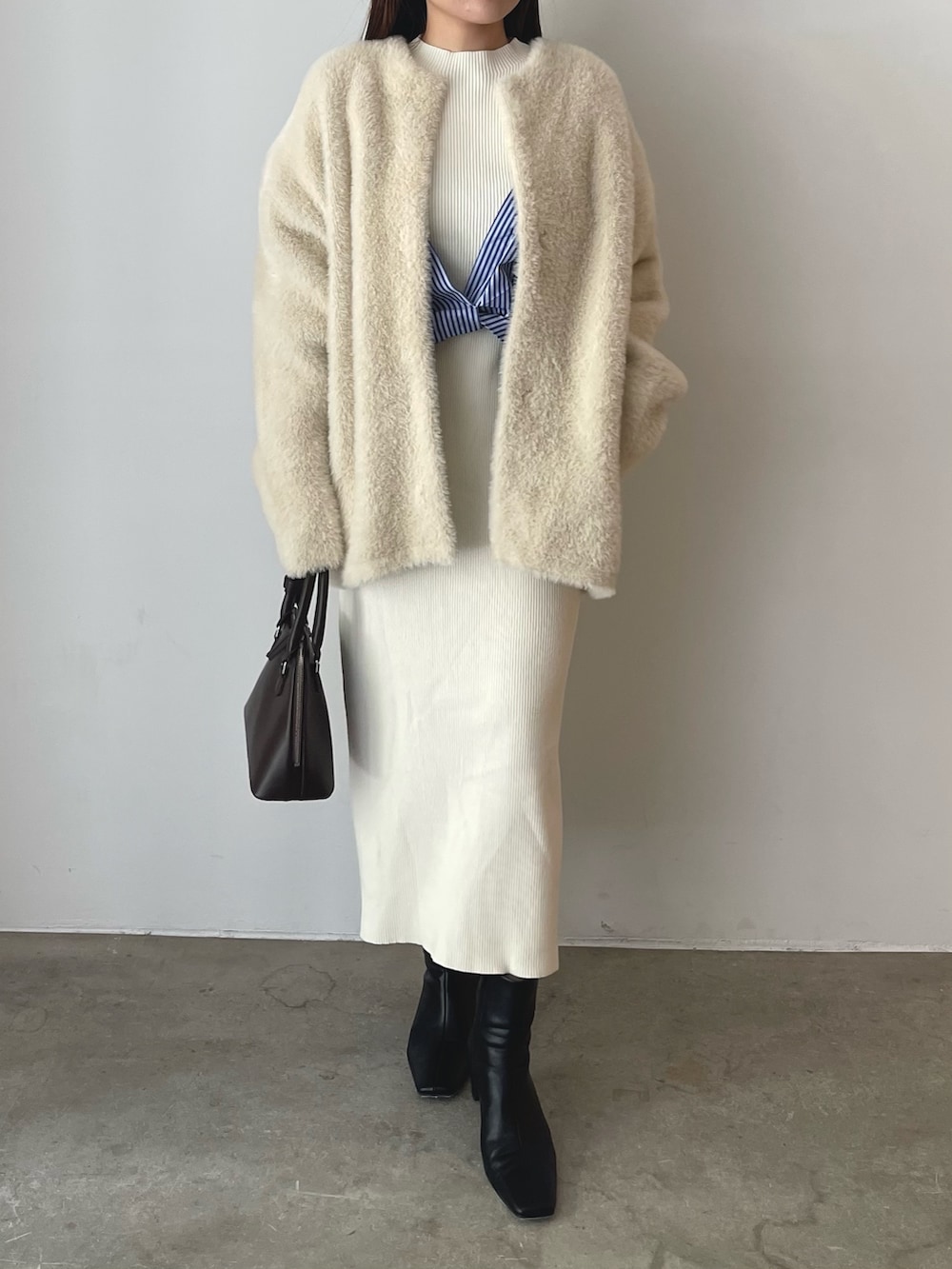 ブラウン系のボストンバッグ、ブラック系のブーツ、ホワイト系のワンピースを着用したレディースの秋コーディネートの5枚目の写真