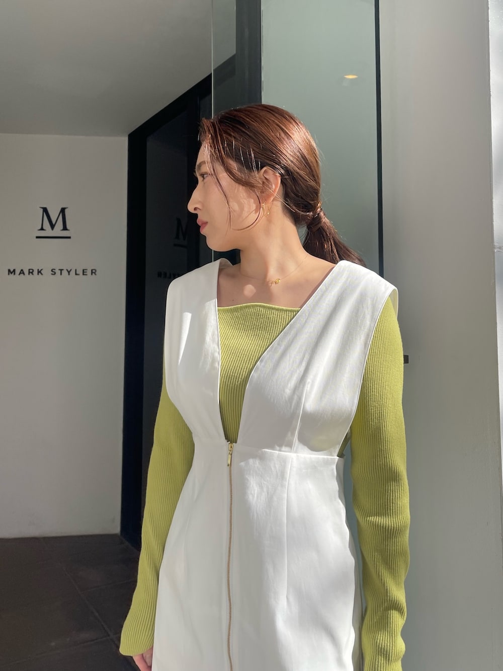 シルバー系のパンプス、グリーン系のニット/セーター、ホワイト系のジャンパースカートを着用したレディースの冬コーディネートの6枚目の写真