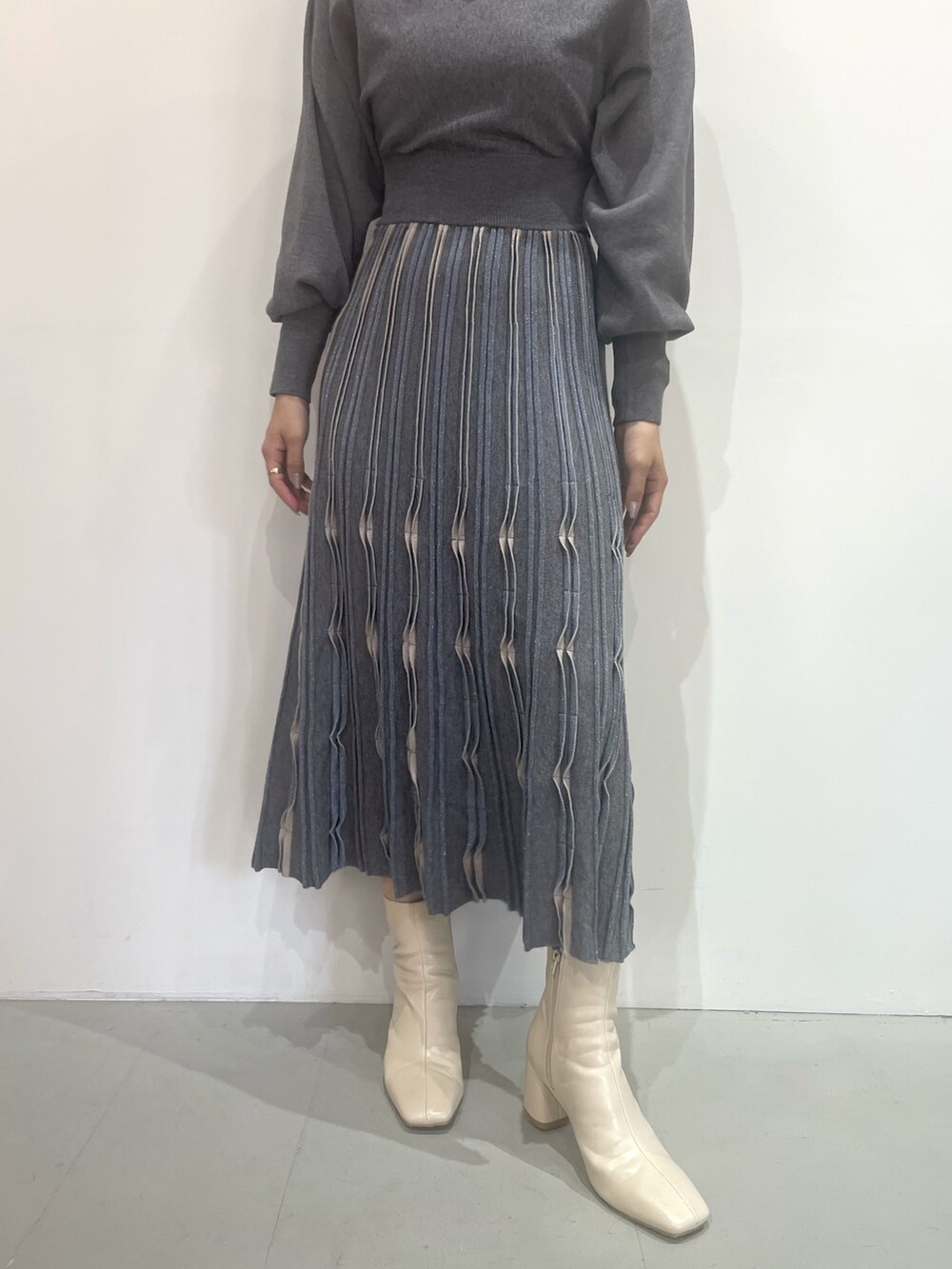 ホワイト系のブーツ、グレー系のワンピースを着用したレディースの秋コーディネートの6枚目の写真