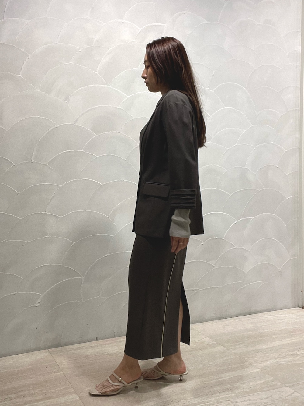 グレー系のスカート、ホワイト系のサンダル、グレー系のニット/セーターを着用したレディースの春コーディネートの4枚目の写真