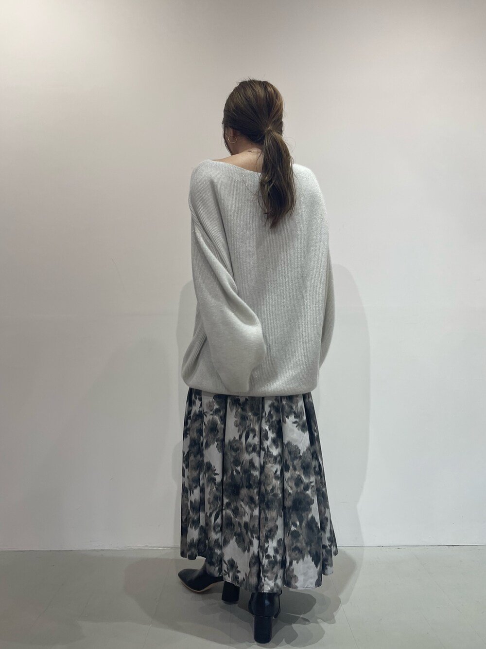 ブラック系のスカート、ブラック系のブーツ、ホワイト系のニット/セーターを着用したレディースの夏コーディネートの4枚目の写真