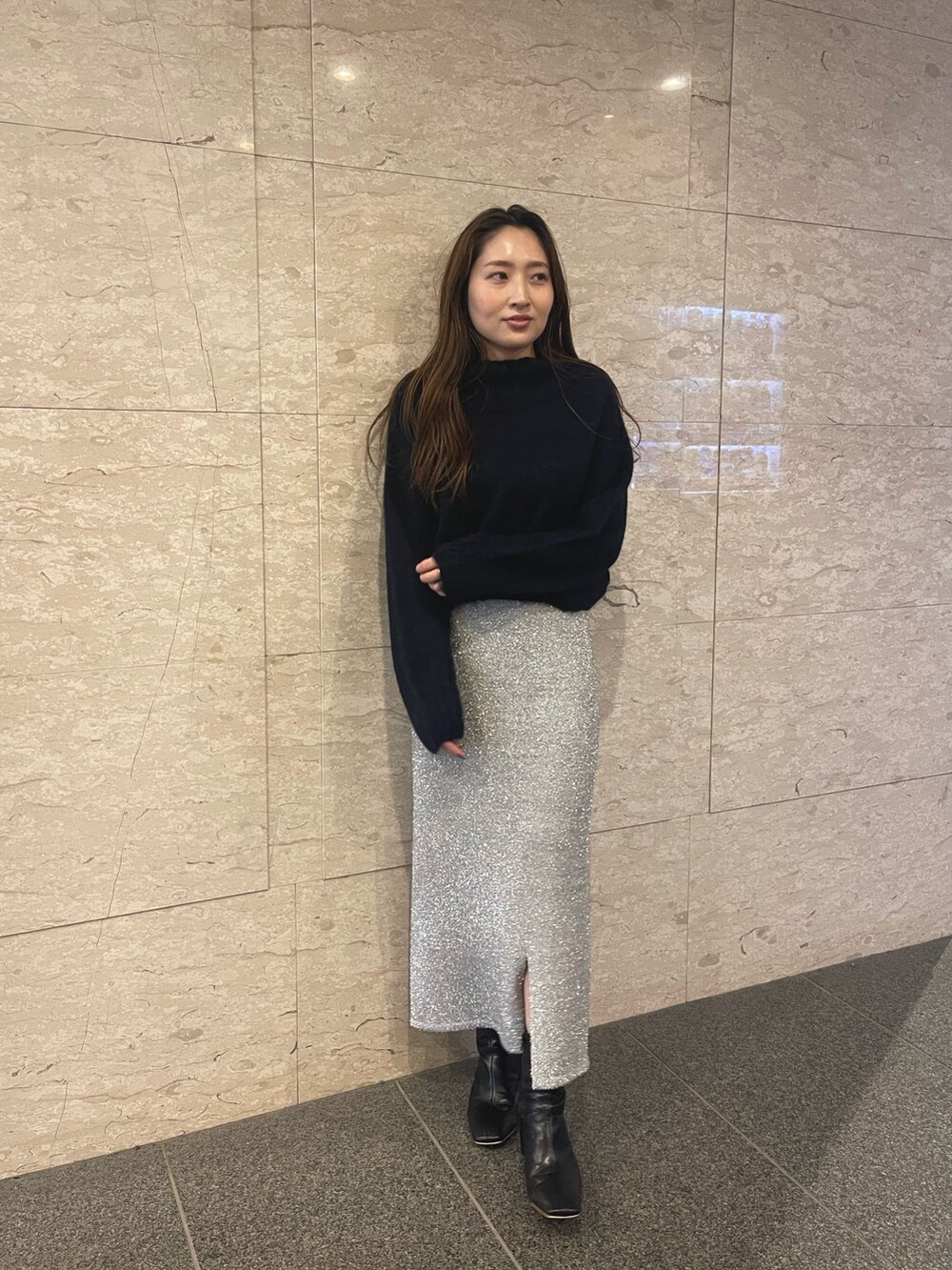 ブラック系のブーツ、ブルー系のニット/セーター、シルバー系のスカートを着用したレディースの冬コーディネートの5枚目の写真