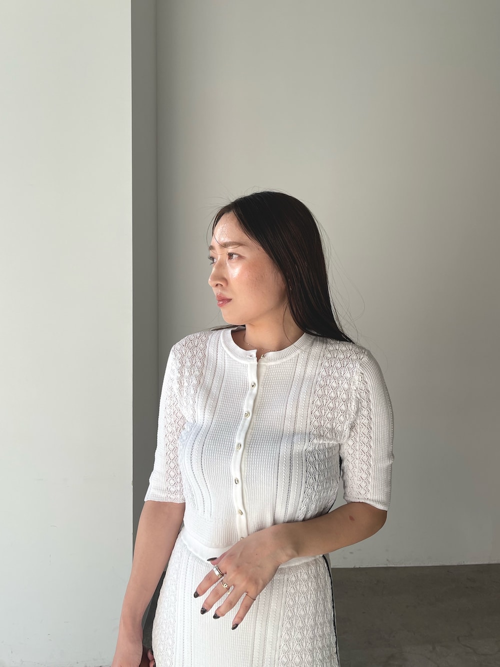 イエロー系のハンドバッグ、シルバー系のパンプス、ホワイト系のワンピースを着用したレディースの冬コーディネートの9枚目の写真