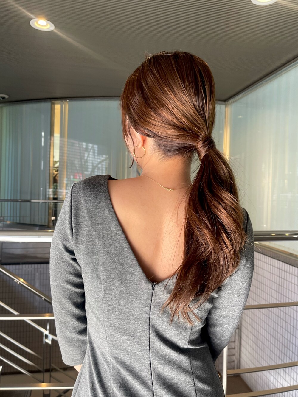 グレー系のワンピース、ホワイト系のショルダーバッグ、シルバー系のパンプスを着用したレディースの冬コーディネートの9枚目の写真