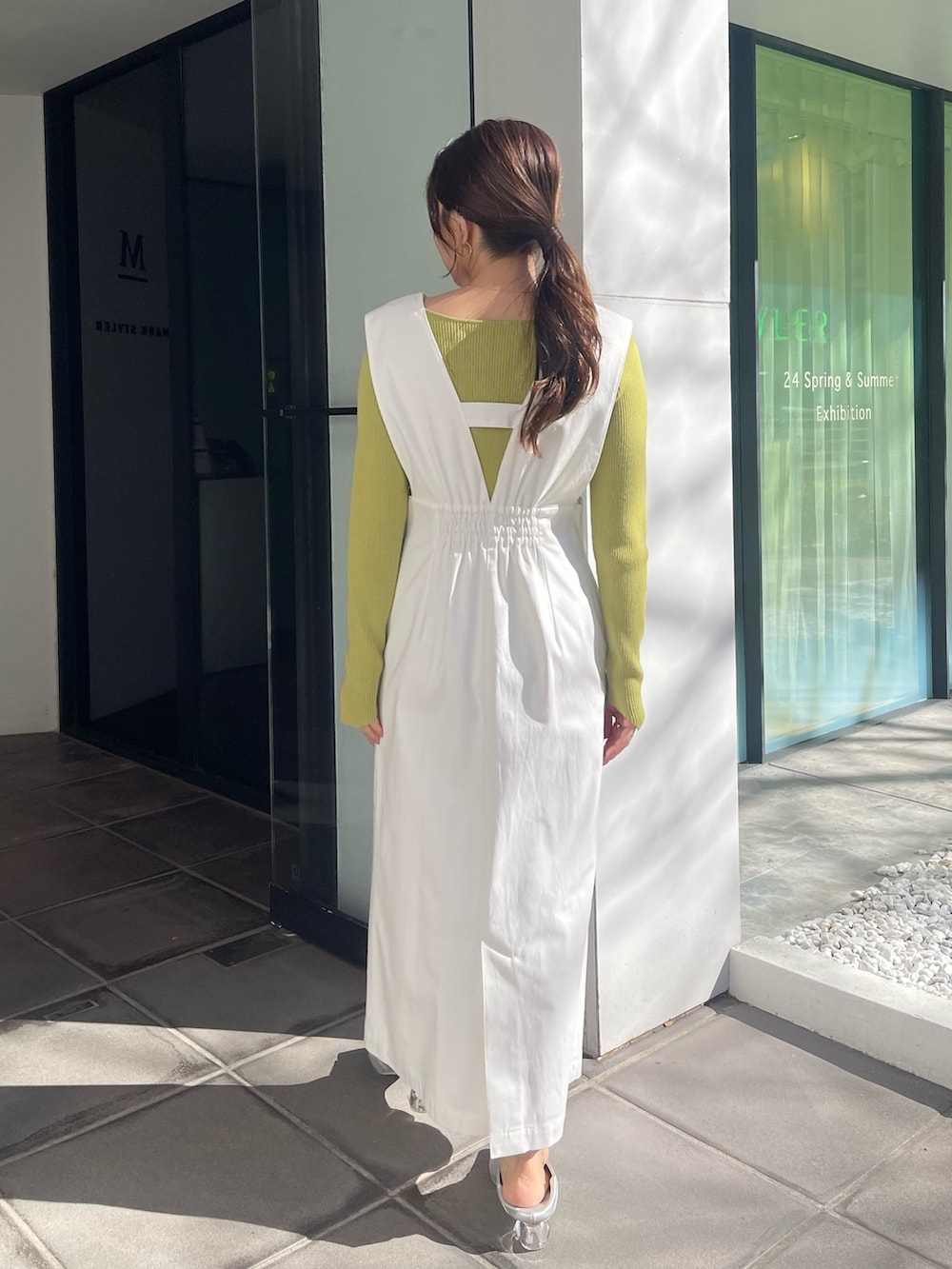 シルバー系のパンプス、グリーン系のニット/セーター、ホワイト系のジャンパースカートを着用したレディースの冬コーディネートの5枚目の写真