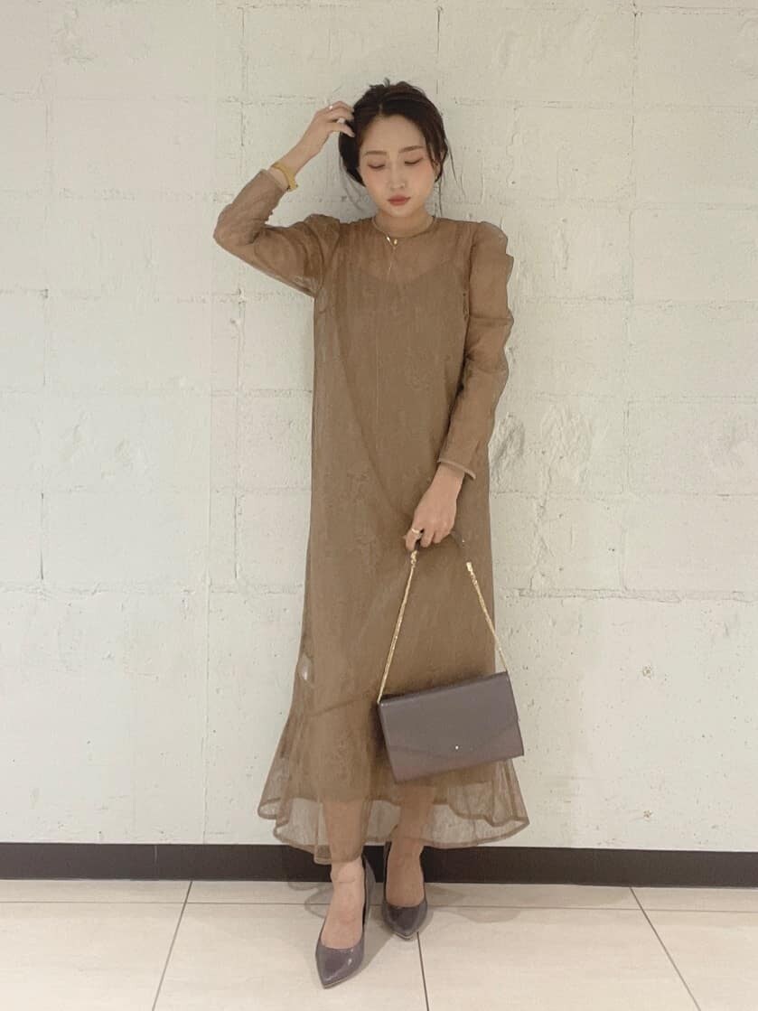 シルバー系のパンプス、シルバー系のハンドバッグ、ベージュ系のドレスを着用したレディースの秋コーディネートの2枚目の写真