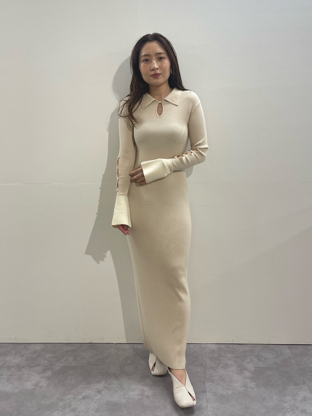 ホワイト系のワンピース、ホワイト系のパンプス、ゴールド系のイヤリングを着用したレディースの冬コーディネートの2枚目の写真