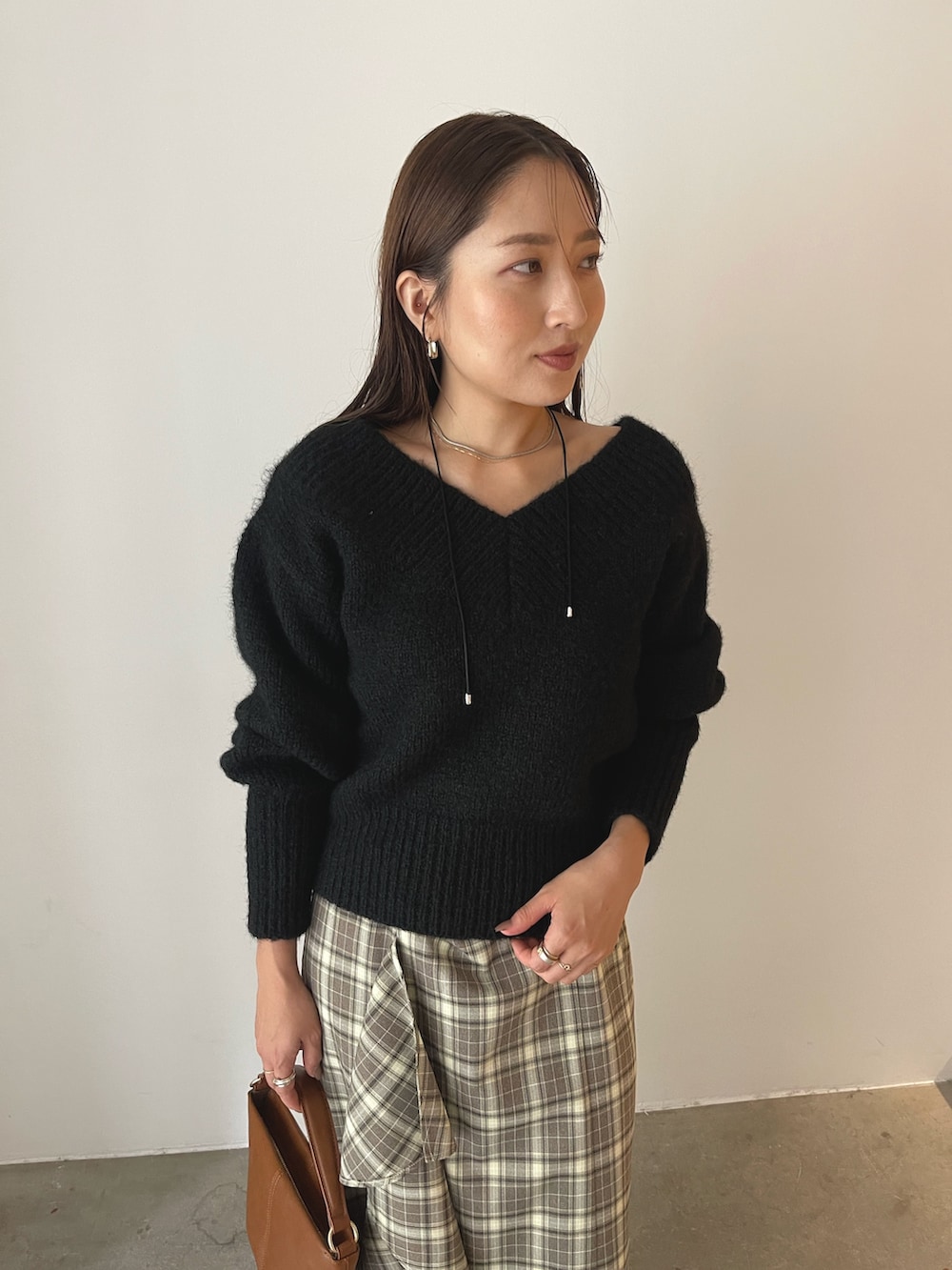 イエロー系のハンドバッグ、ブラウン系のブーツ、ブラウン系のスカートを着用したレディースの秋コーディネートの10枚目の写真