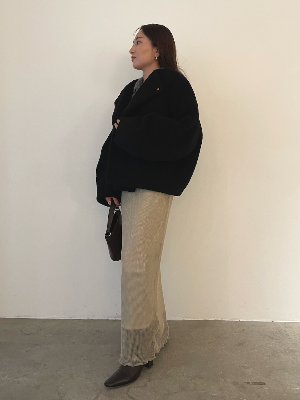 ブラック系のブルゾン、ブラウン系のハンドバッグ、ブラウン系のブーツを着用したレディースの秋コーディネートの4枚目の写真