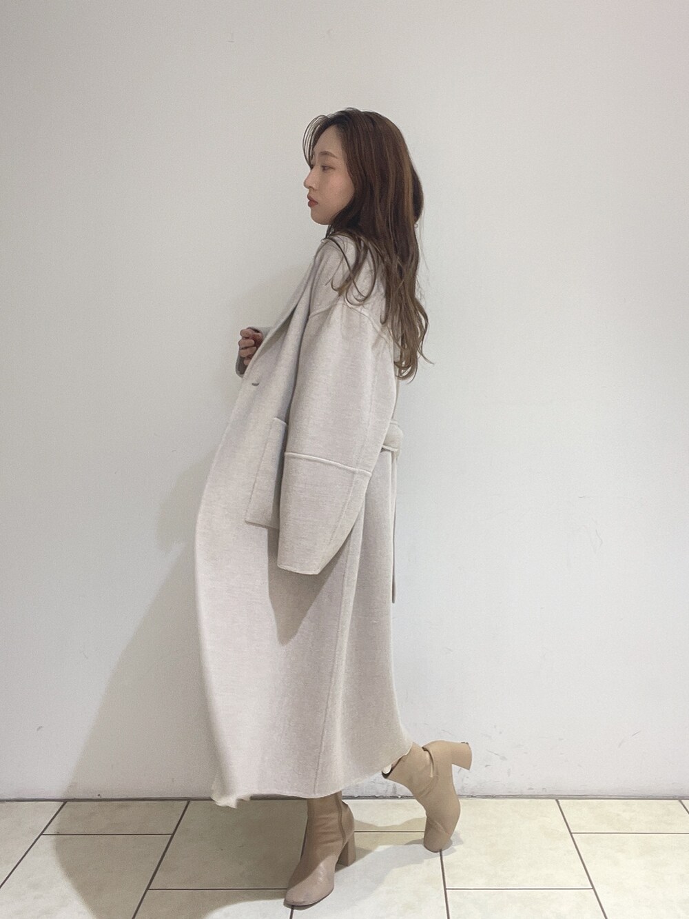 ホワイト系のスカート、ベージュ系のその他アウター、グリーン系のニット/セーターを着用したレディースの冬コーディネートの8枚目の写真