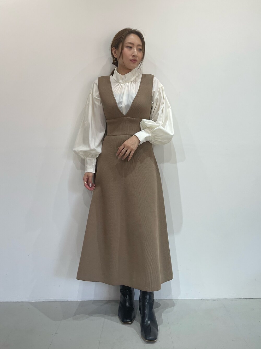 ベージュ系のジャンパースカート、ホワイト系のシャツ/ブラウス、ブラック系のブーツを着用したレディースの秋コーディネートの3枚目の写真