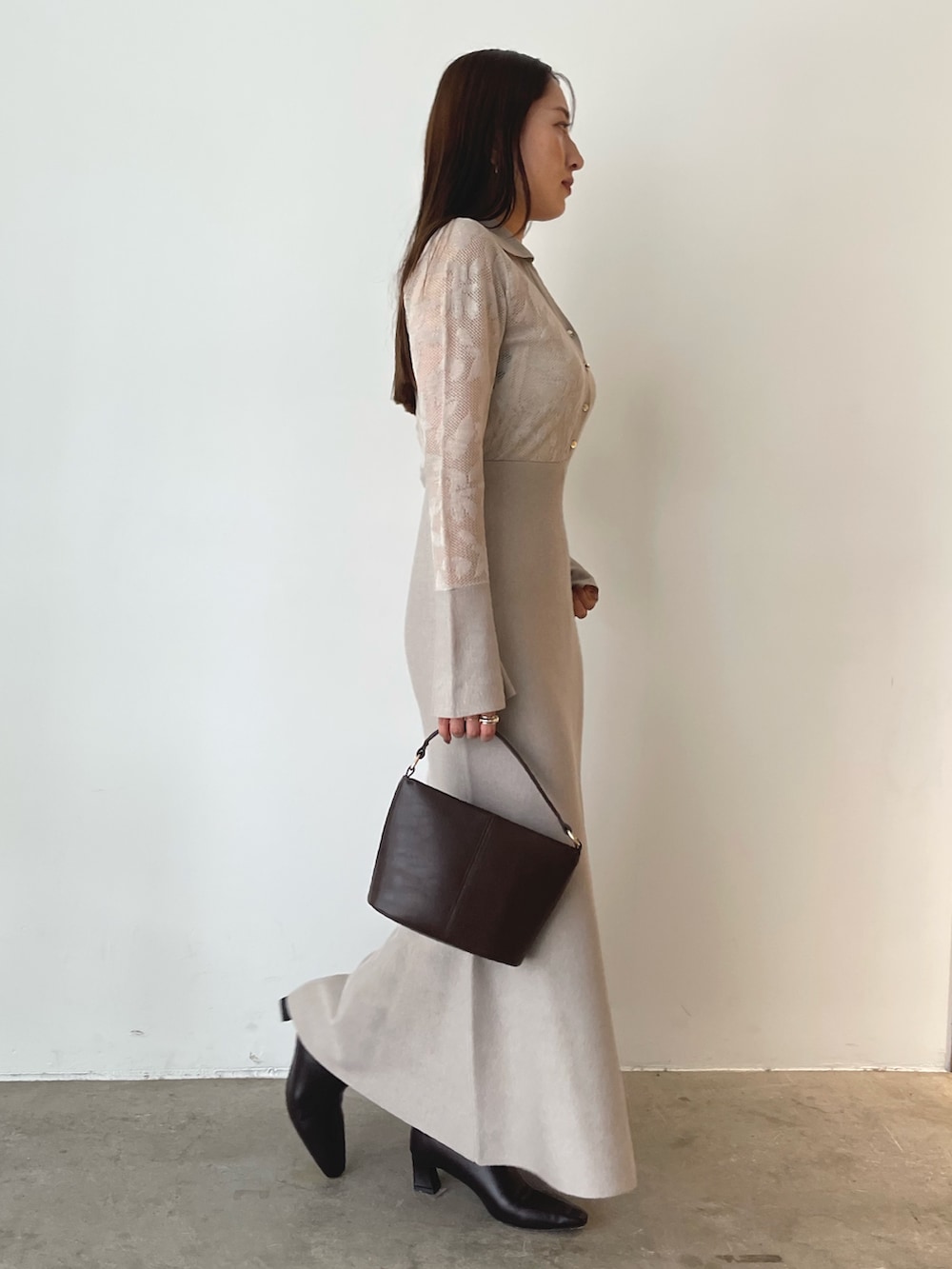 ブラウン系のハンドバッグ、ベージュ系のワンピース、ブラウン系のブーツを着用したレディースの秋コーディネートの6枚目の写真
