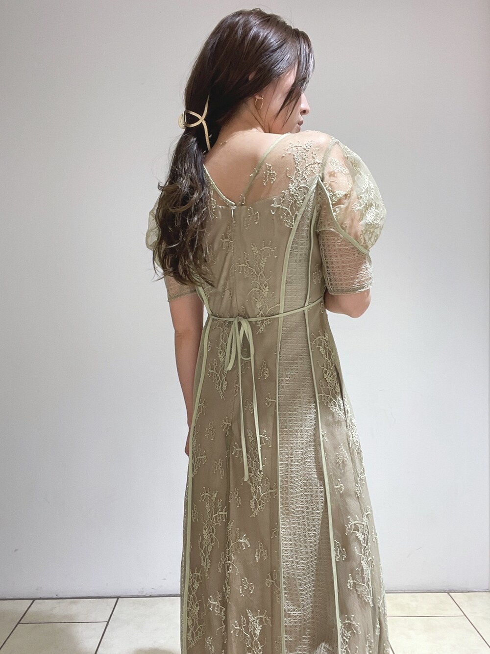 ゴールド系のハンドバッグ、グリーン系のドレス、ゴールド系のパンプスを着用したレディースの冬コーディネートの9枚目の写真