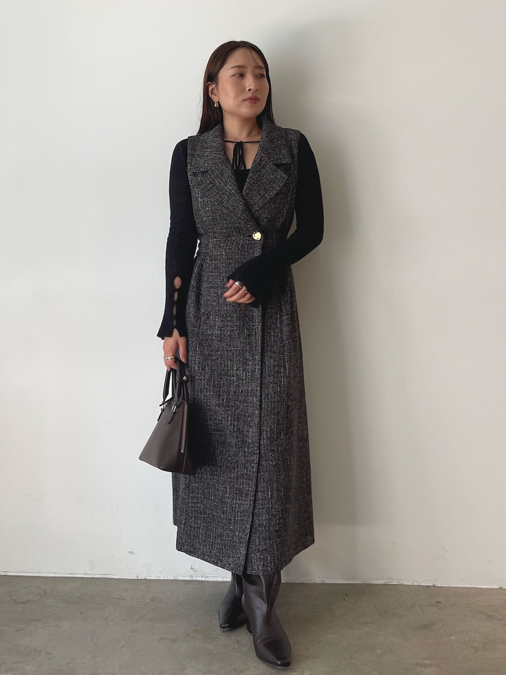 ブラウン系のブーツ、ブラウン系のボストンバッグ、ブラック系のニット/セーターを着用したレディースの秋コーディネートの3枚目の写真