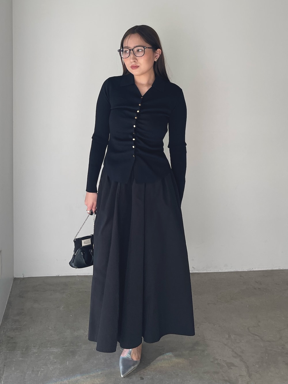 シルバー系のパンプス、ブラック系のワンピース、ゴールド系のピアス（両耳用）を着用したレディースの冬コーディネートの3枚目の写真