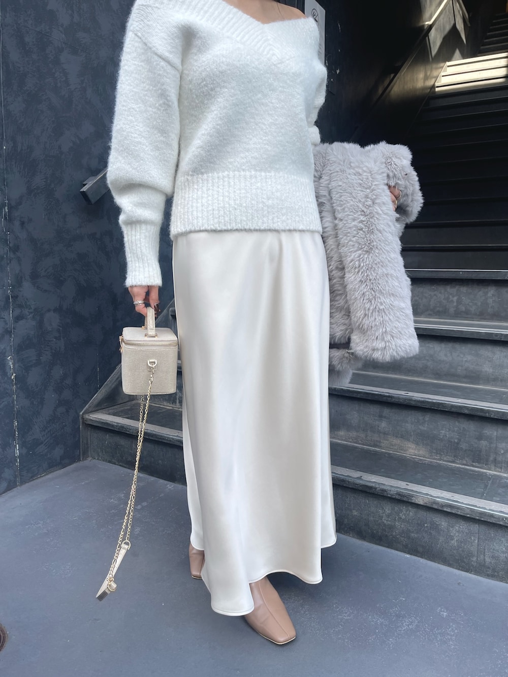 ホワイト系のニット/セーター、グレー系のその他アウター、ゴールド系のハンドバッグを着用したレディースの冬コーディネートの8枚目の写真