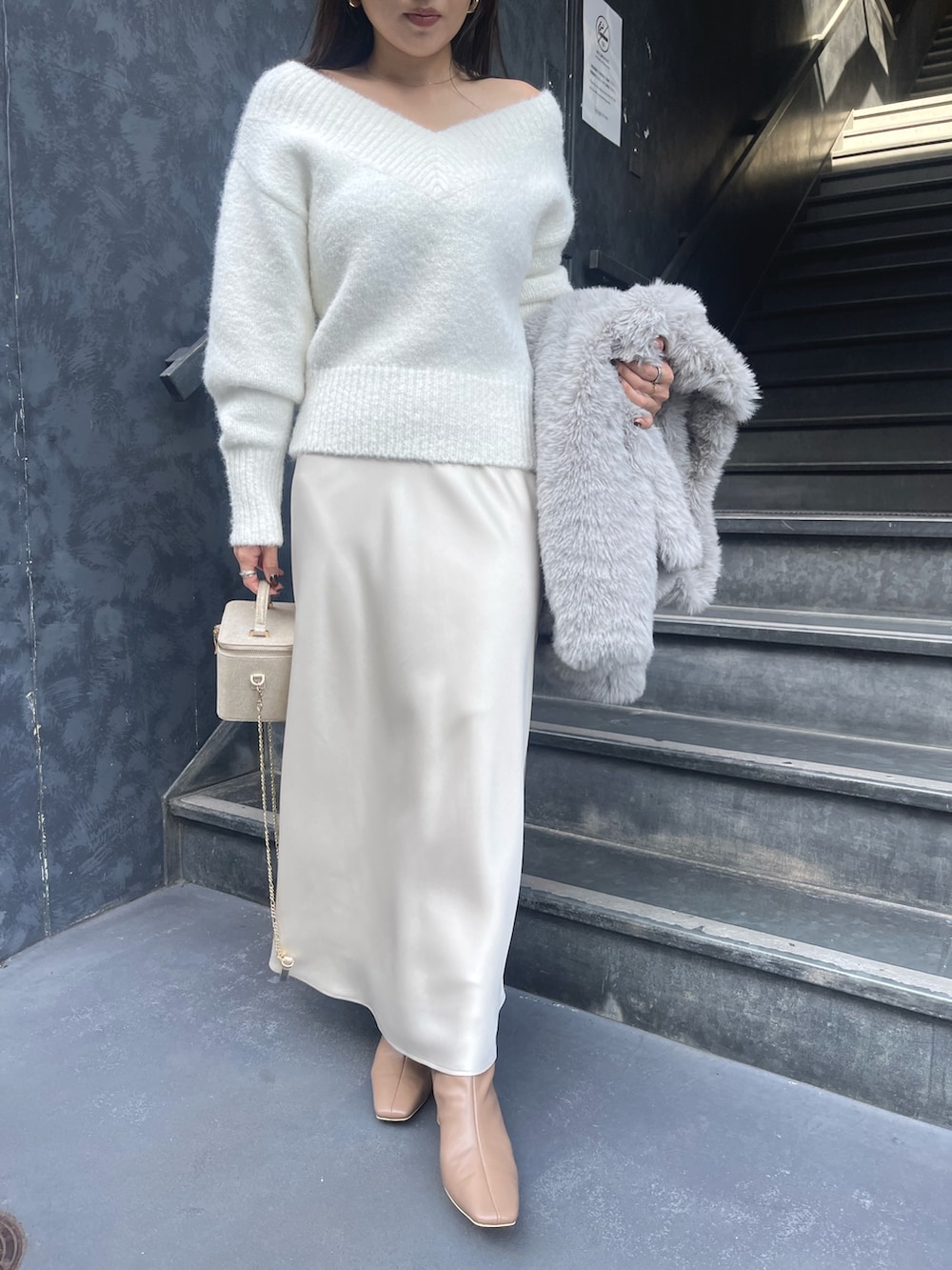 ホワイト系のニット/セーター、グレー系のその他アウター、ゴールド系のハンドバッグを着用したレディースの冬コーディネートの7枚目の写真