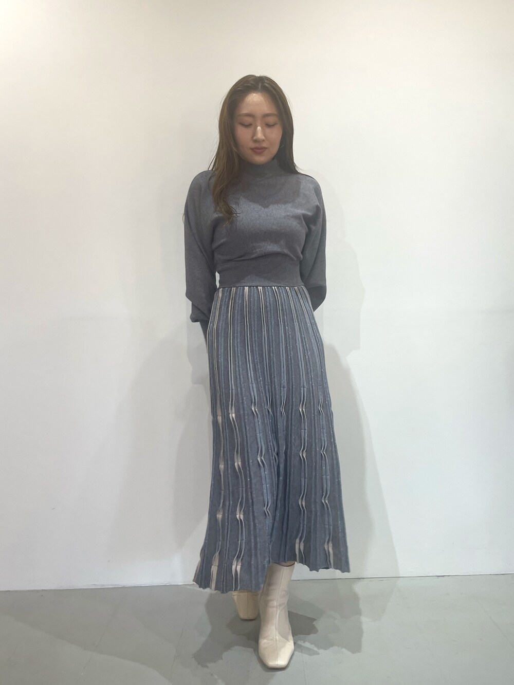 ホワイト系のブーツ、グレー系のワンピースを着用したレディースの秋コーディネートの3枚目の写真