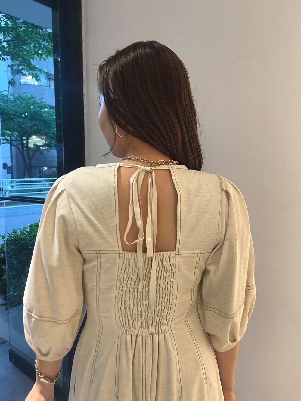 ホワイト系のスニーカー、ホワイト系のワンピース、ゴールド系のネックレスを着用したレディースの春コーディネートの7枚目の写真