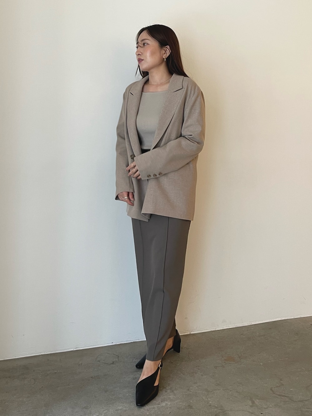 ブラック系のパンプス、グレー系のスカート、ベージュ系のニット/セーターを着用したレディースの秋コーディネートの2枚目の写真