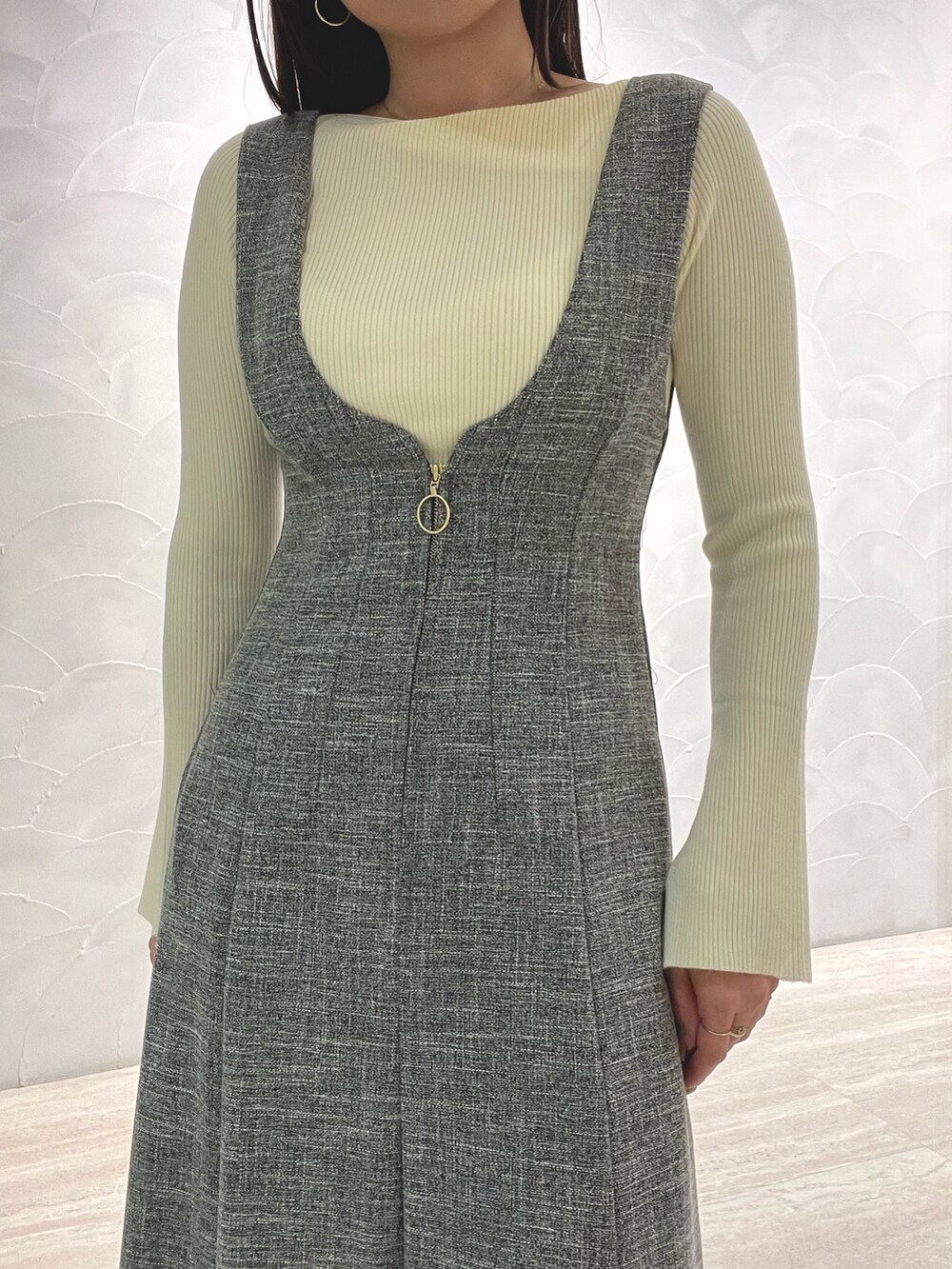 ホワイト系のサンダル、ホワイト系のニット/セーター、グレー系のジャンパースカートを着用したレディースの春コーディネートの6枚目の写真