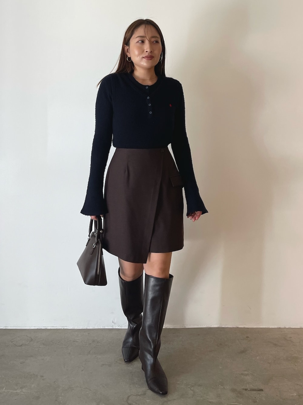 ブラウン系のボストンバッグ、ブラウン系のスカート、ブルー系のニット/セーターを着用したレディースの夏コーディネートの4枚目の写真