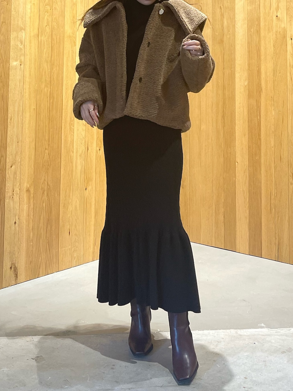 ブラウン系のブルゾン、レッド系のブーツ、ブラック系のワンピースを着用したレディースの秋コーディネートの5枚目の写真