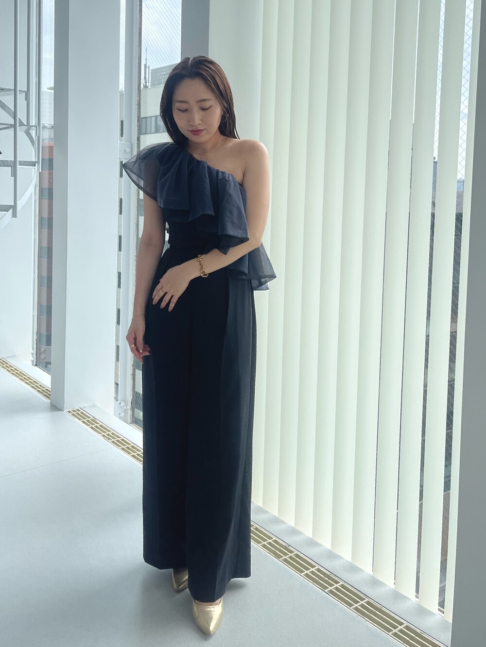 ゴールド系のパンプス、ブラック系のパンツドレスを着用したレディースの夏コーディネートの6枚目の写真