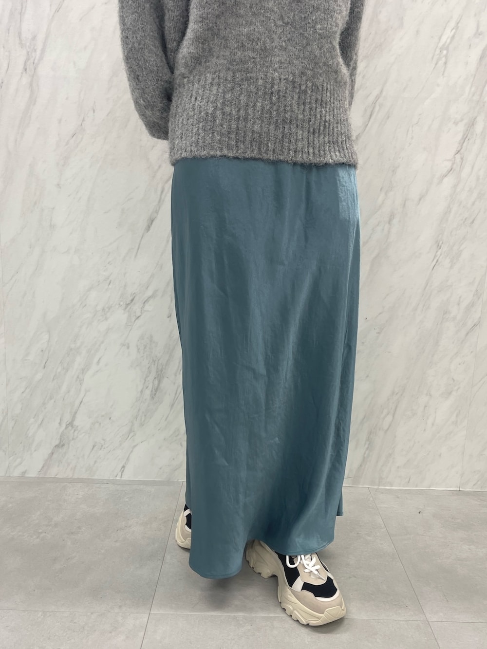 グレー系のニット/セーター、ブルー系のスカート、ブラック系のスニーカーを着用したレディースの冬コーディネートの10枚目の写真