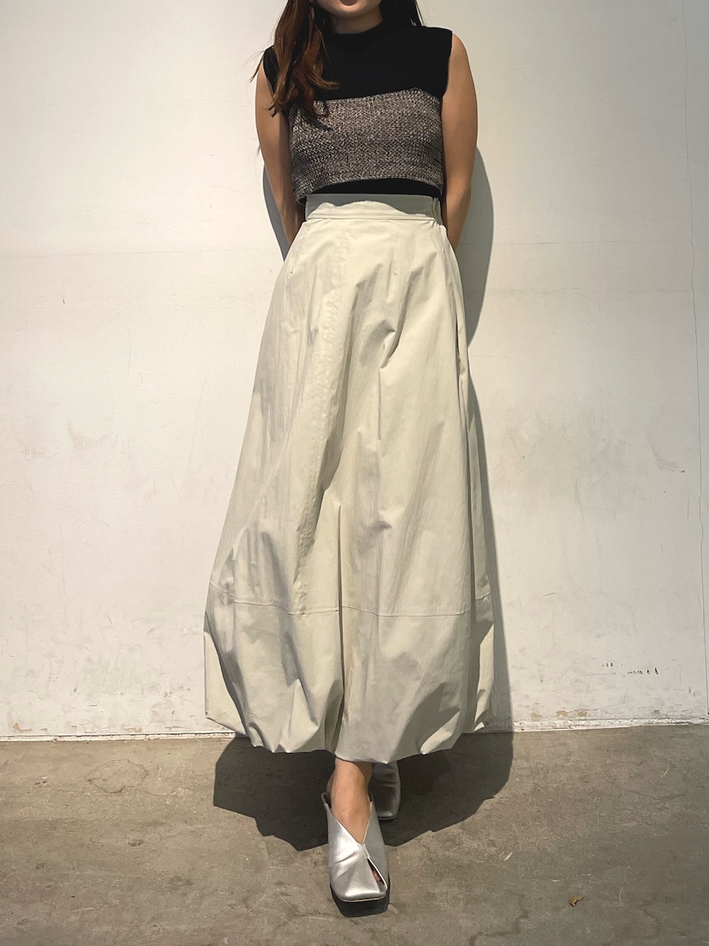 シルバー系のパンプス、ブラック系のニット/セーター、ホワイト系のスカートを着用したレディースの春コーディネートの3枚目の写真