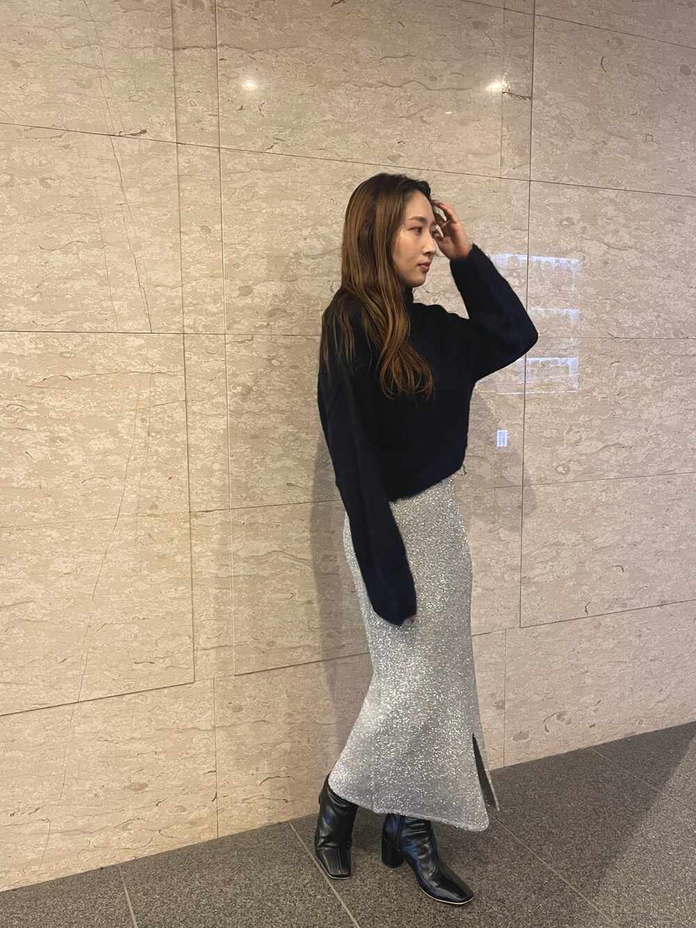 ブラック系のブーツ、ブルー系のニット/セーター、シルバー系のスカートを着用したレディースの冬コーディネートの4枚目の写真