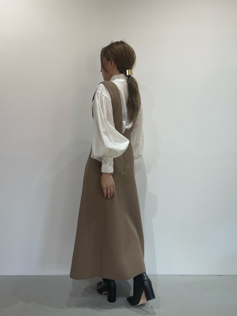 ベージュ系のジャンパースカート、ホワイト系のシャツ/ブラウス、ブラック系のブーツを着用したレディースの秋コーディネートの5枚目の写真