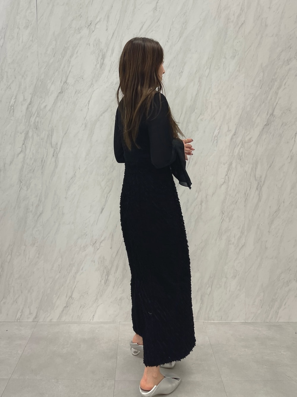 シルバー系のパンプス、ブラック系のワンピース、ゴールド系のネックレスを着用したレディースの春コーディネートの3枚目の写真