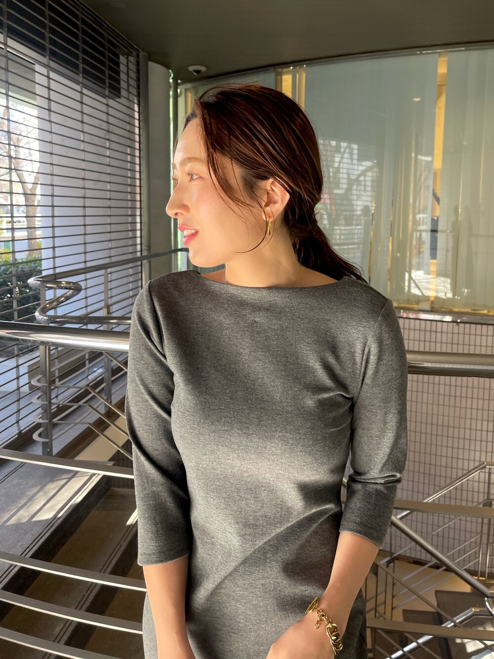 グレー系のワンピース、ホワイト系のショルダーバッグ、シルバー系のパンプスを着用したレディースの冬コーディネートの8枚目の写真