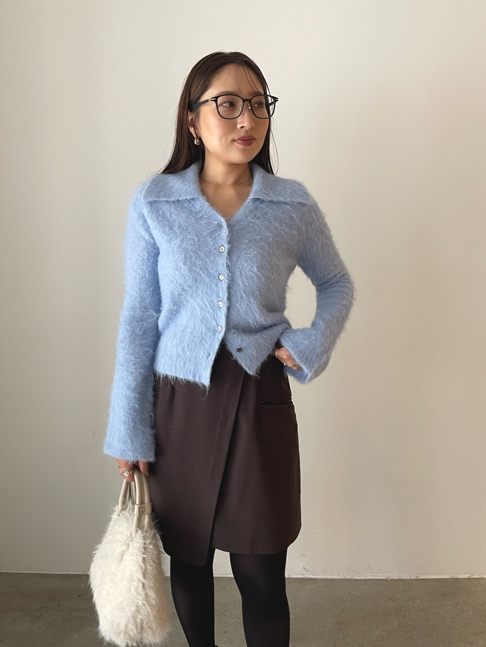 ホワイト系のボストンバッグ、ブラウン系のスカート、ブラック系のローファーを着用したレディースの秋コーディネートの9枚目の写真