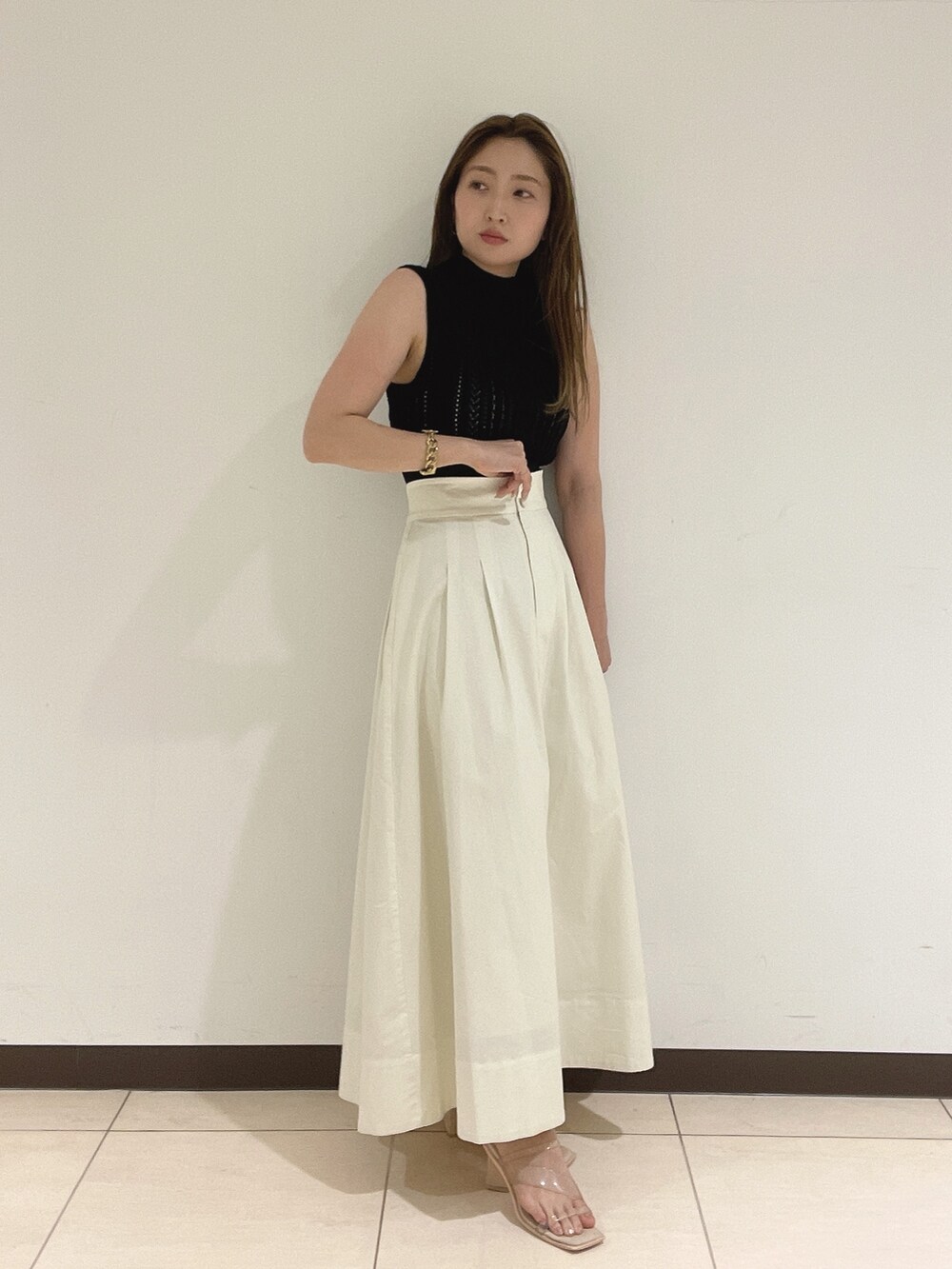 ブラック系のニット/セーター、ホワイト系のスカート、その他のサンダルを着用したレディースの夏コーディネートの5枚目の写真