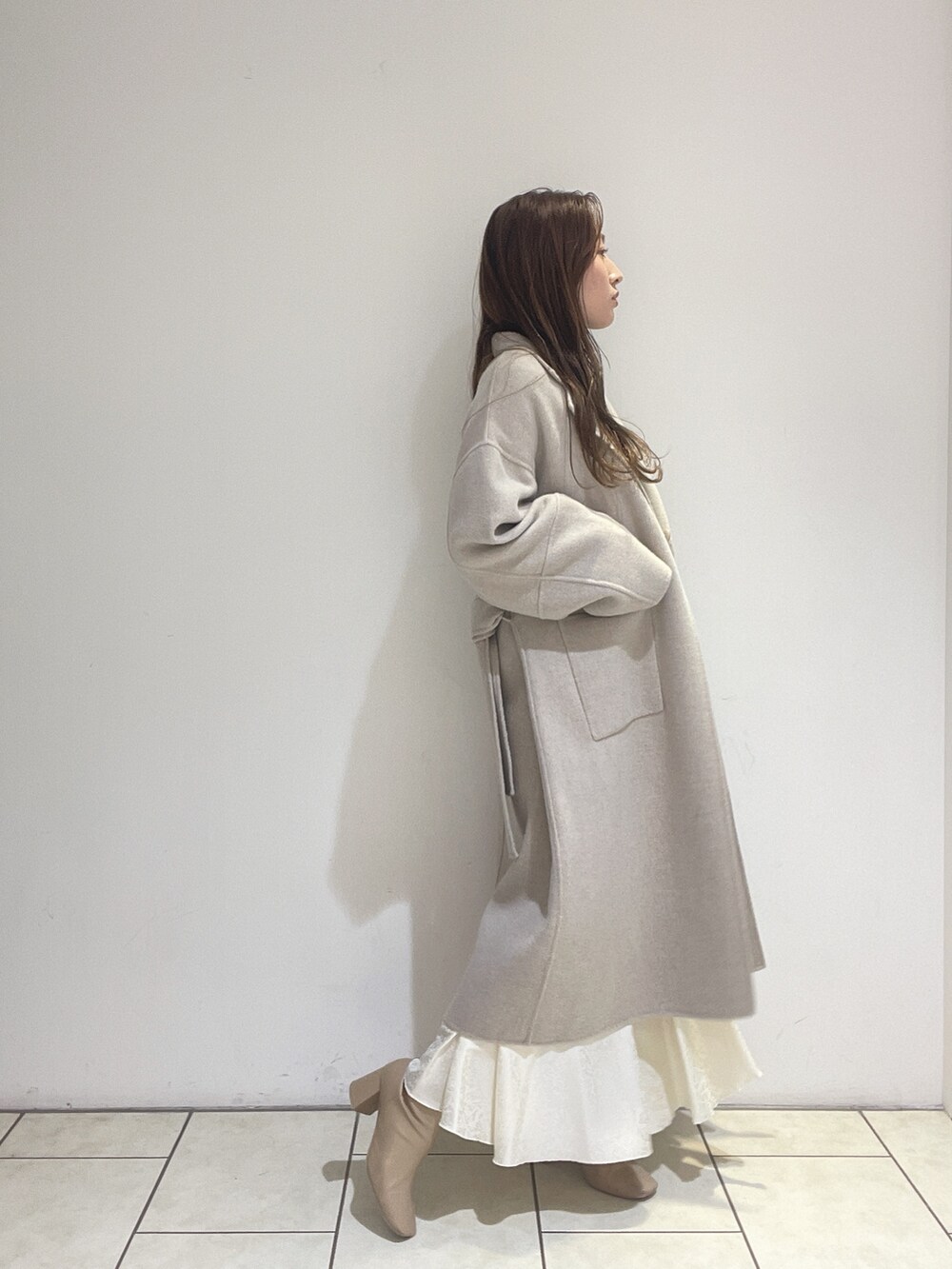 ホワイト系のスカート、ベージュ系のその他アウター、グリーン系のニット/セーターを着用したレディースの冬コーディネートの5枚目の写真